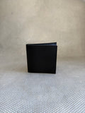 Black leather wallet on a textured beige surface