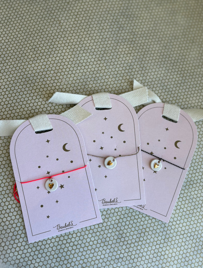 pink cardboard packaging and string charm bracelets with heart.