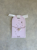 pink cardboard packaging and gold string charm bracelet with heart.