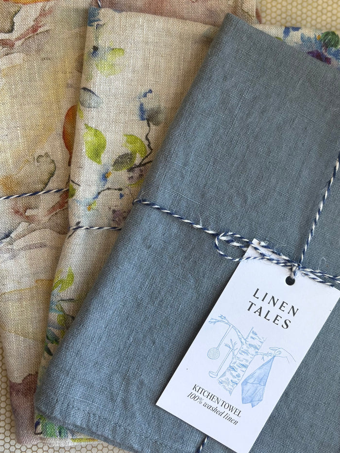 stacked kitchen towels in varying colors. Linen Tales 100% linen 18''x26''