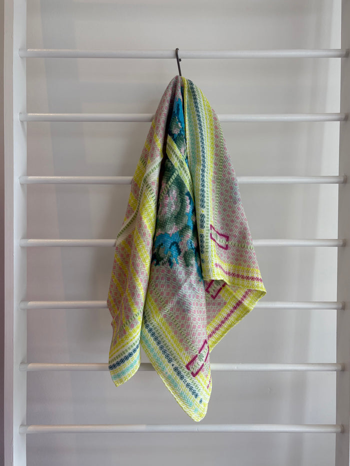 floral brightly colored scarf on rack pink, blue, green, yellow design.