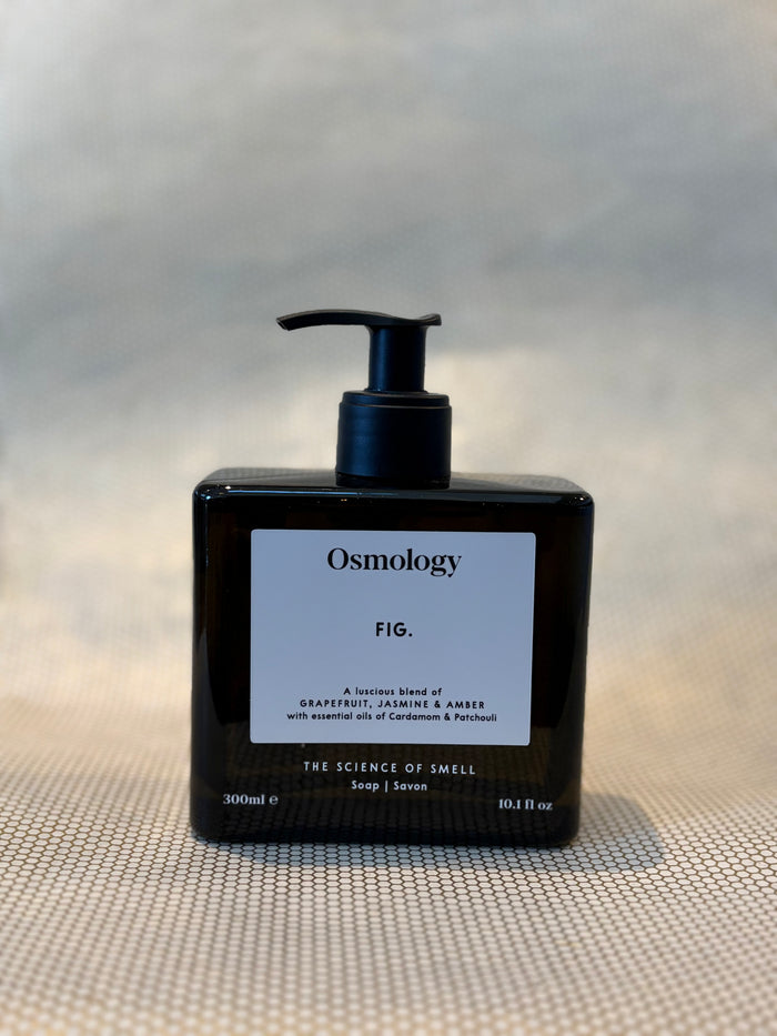 front of liquid soap bottle in Fig scent by Osmology. glass bottle hand soap on neutral background.
