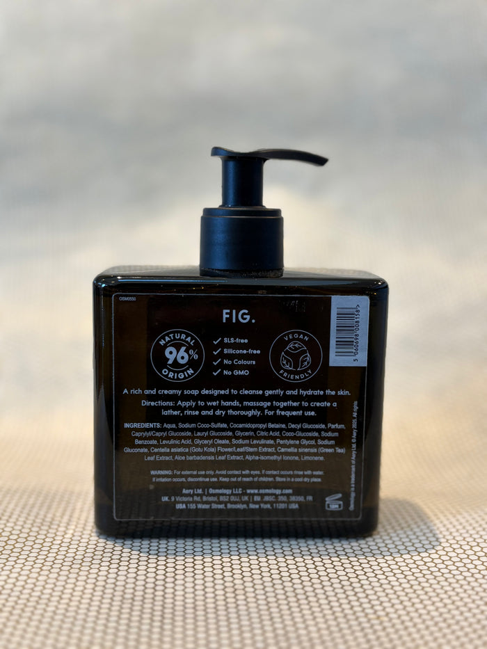 back of liquid soap bottle in Fig scent by Osmology. glass bottle hand soap on neutral background.