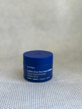 Blue traveler jar of Ursula Major Golden Hour Recovery Cream on a textured beige background