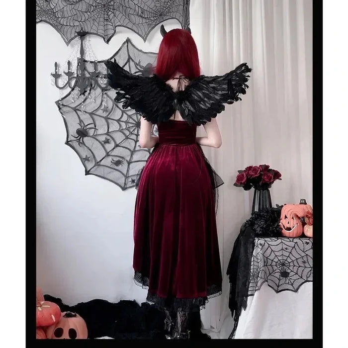 Person in a red dress with black wings standing in a Halloween-themed room.