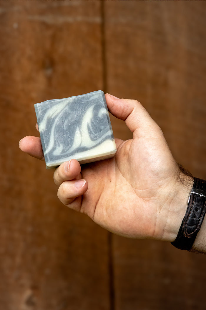Rustic Strength - Hand holding a 3.5 oz bar of Detoxifying Charcoal Soap