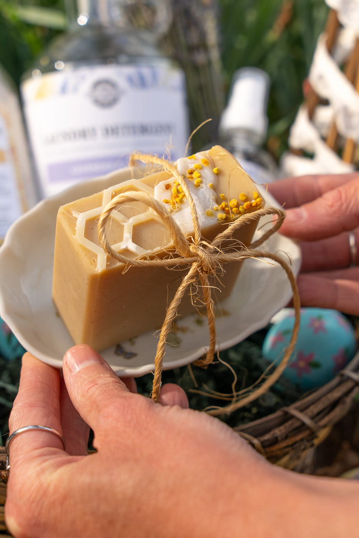 Rustic Strength - Person holding a bar of Milk & Honey soap on a tray wrapped in twine.