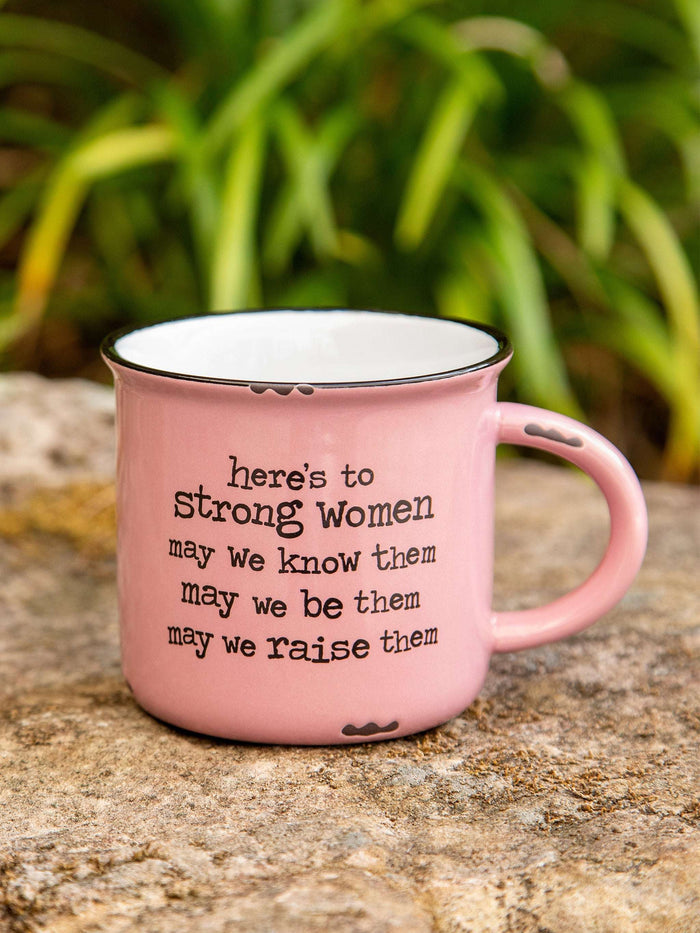 Pink mug with motivational quote on a stone surface with greenery in the background