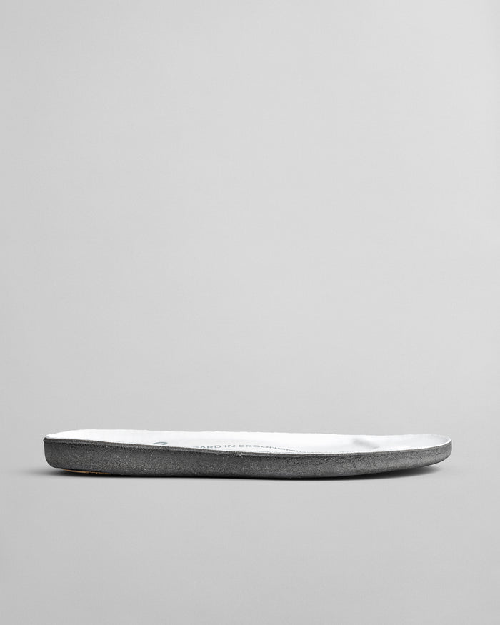 Gray suede insole with white cushioned footbed and curved edges, shown from side angle.