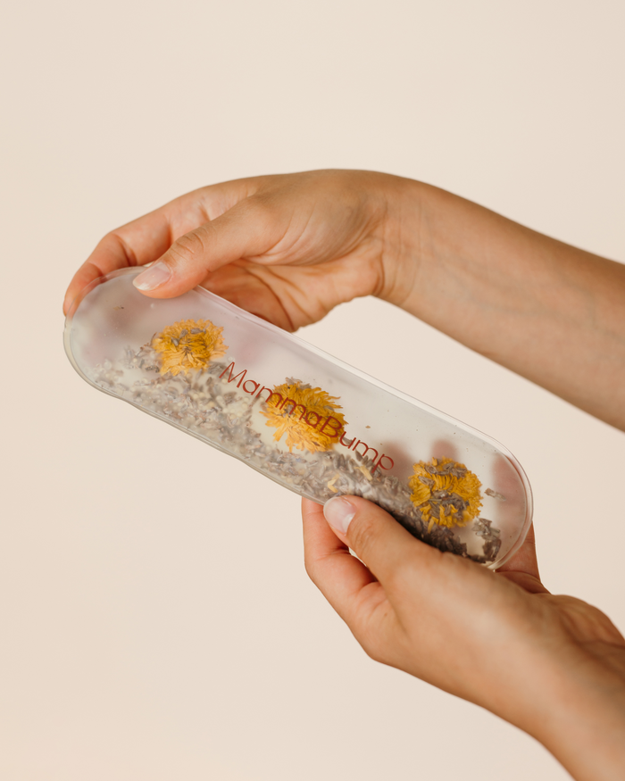Hands flexing the MammaBump Perineal Hot & Cold Therapy Pack showing its soft, reusable design with chamomile and lavender inside
