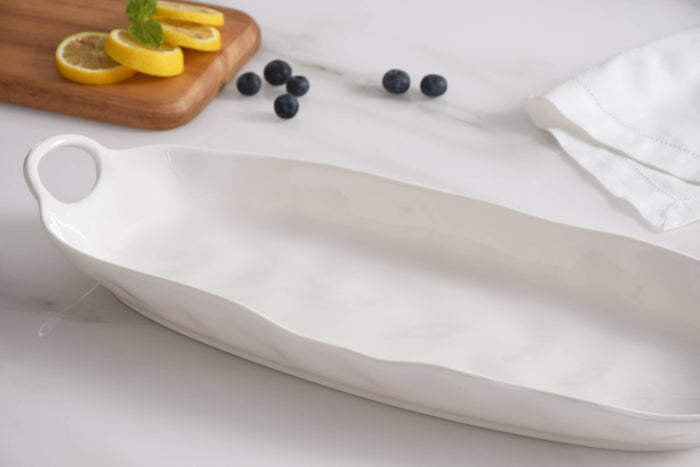 White ceramic platter on a light surface with lemons and blueberries.