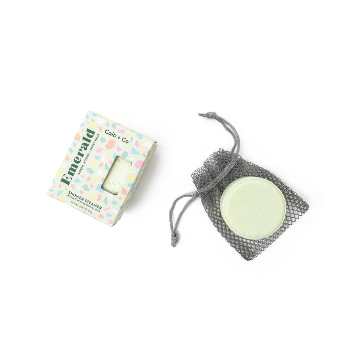 Emerald shower steamer and its packaging against a white background
