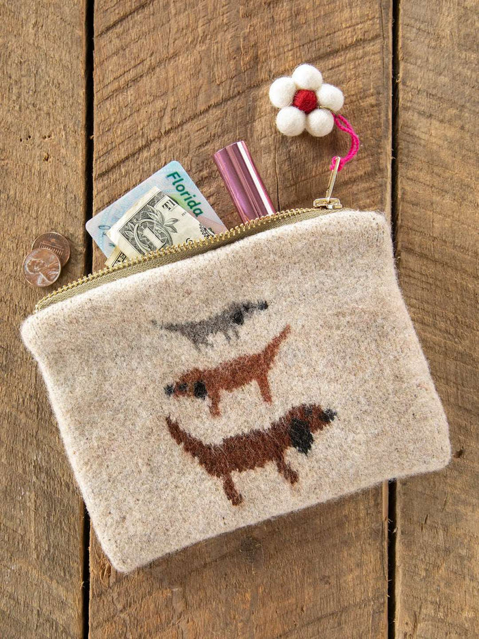 Beige pouch with embroidered dogs on a wooden surface