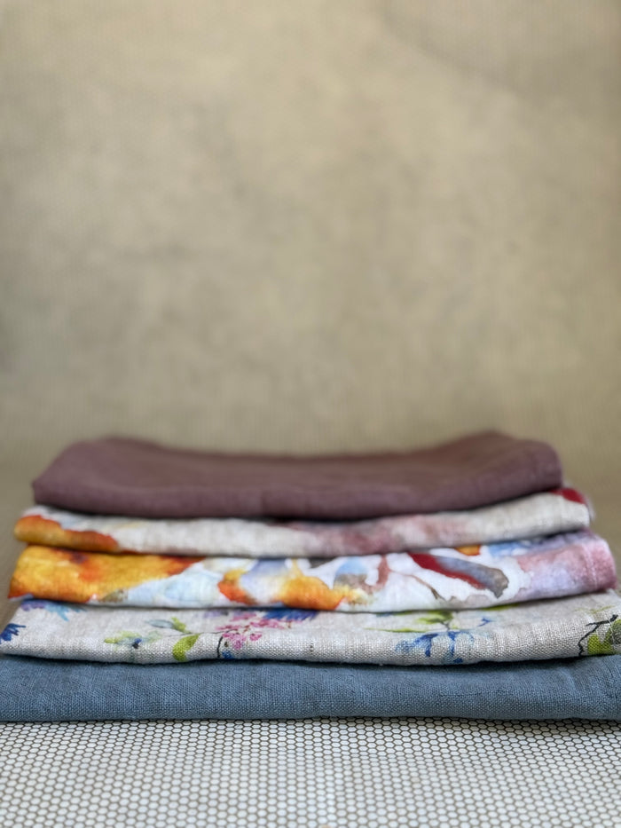 stacked kitchen towels in varying colors. Linen Tales 100% linen 18''x26''