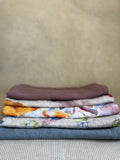 stacked kitchen towels in varying colors. Linen Tales 100% linen 18''x26''