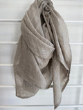 Beige linen scarf draped over a white lattice background