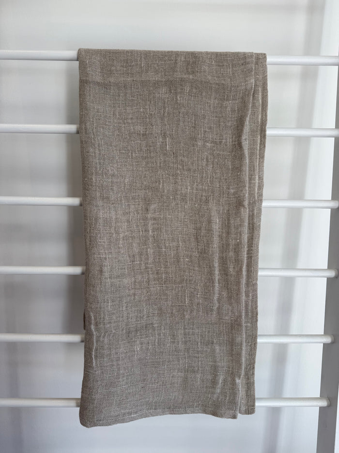 Beige linen scarf draped over a white lattice background