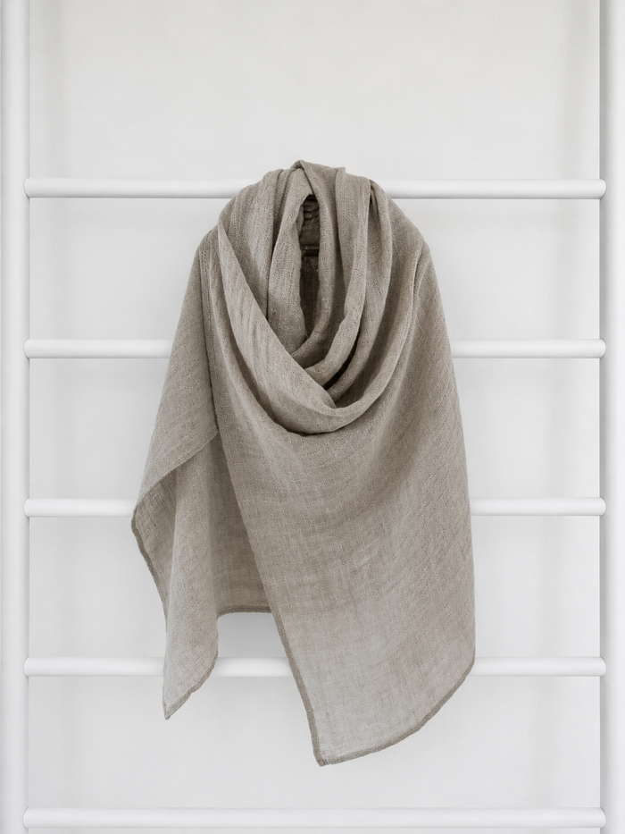 Beige linen scarf draped over a white lattice background