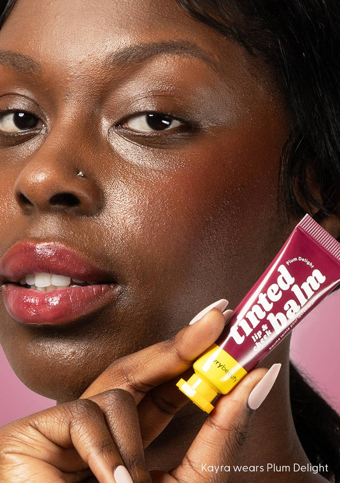 Woman holding a tube of tanned lip balm with a close-up of her lips.