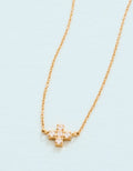 Gold cross necklace on a light blue background