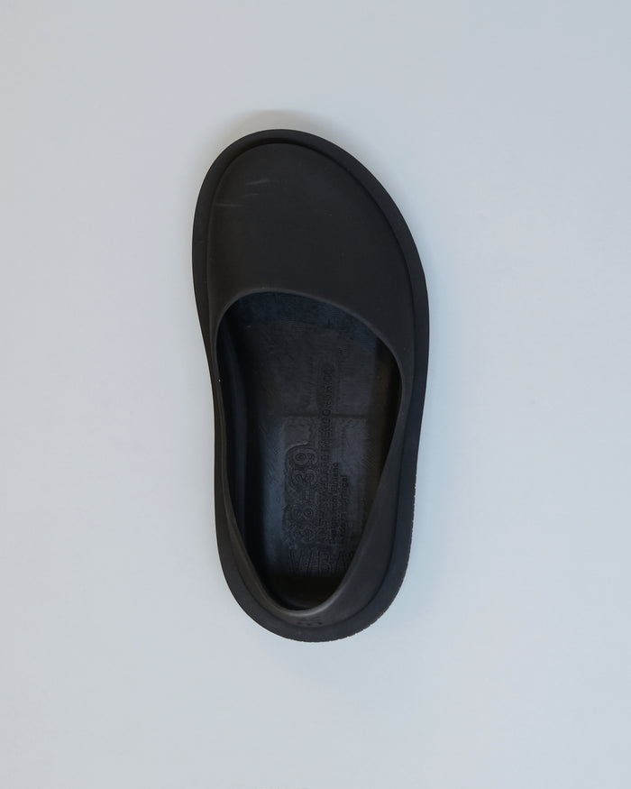 Black slip-on slipper with textured natural rubber sole and molded footbed, viewed from above.