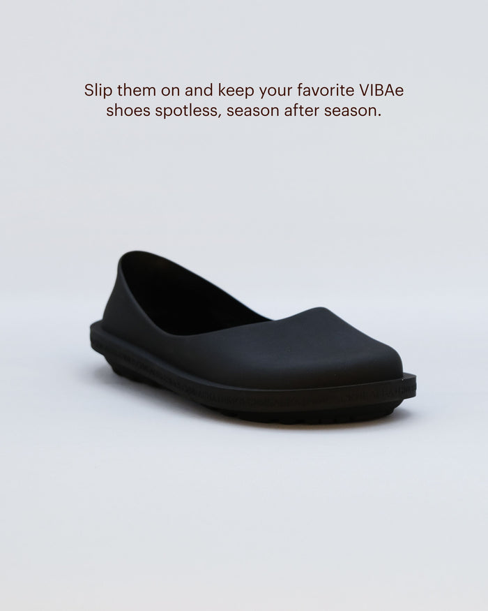 Black slip-on clog with curved upper and thick sole, viewed from the side.