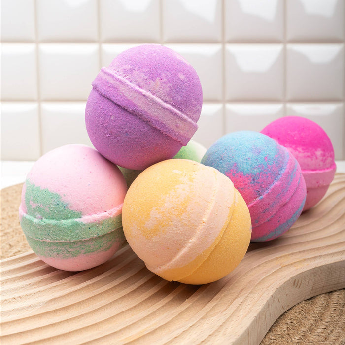 a collection of multicolored bath bombs arranged atop a wooden surface