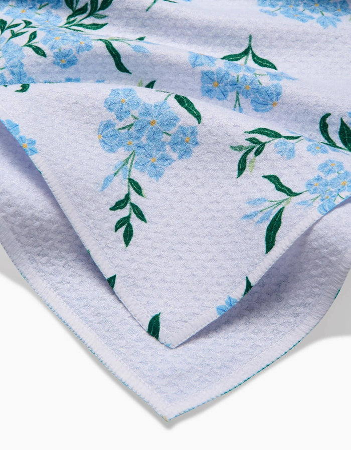 Floral-patterned towel with blue flowers and green leaves on a white background