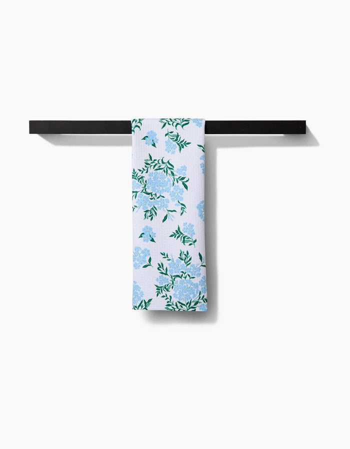 Floral-patterned towel hanging on a black metal rack against a white background