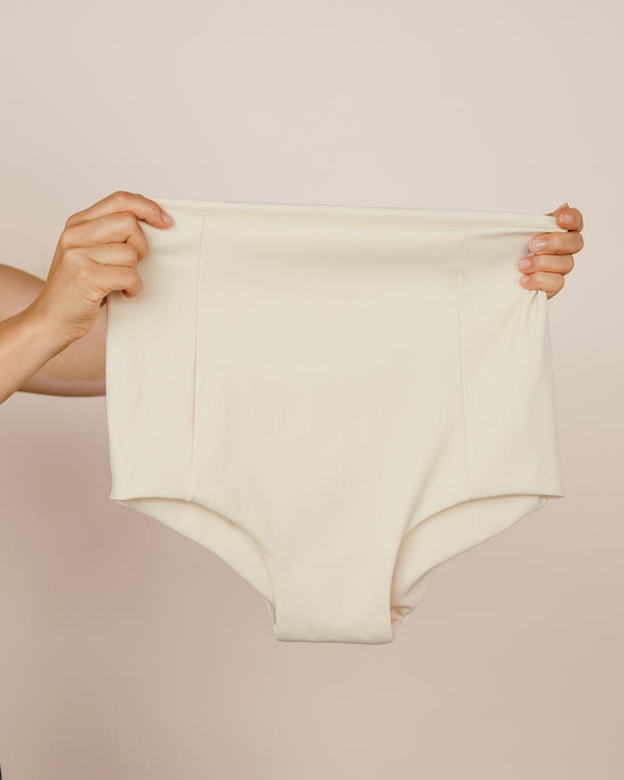 Hands holding up the cream MammaBump Postpartum Soothing Brief, high-waisted and seamless for postpartum recovery