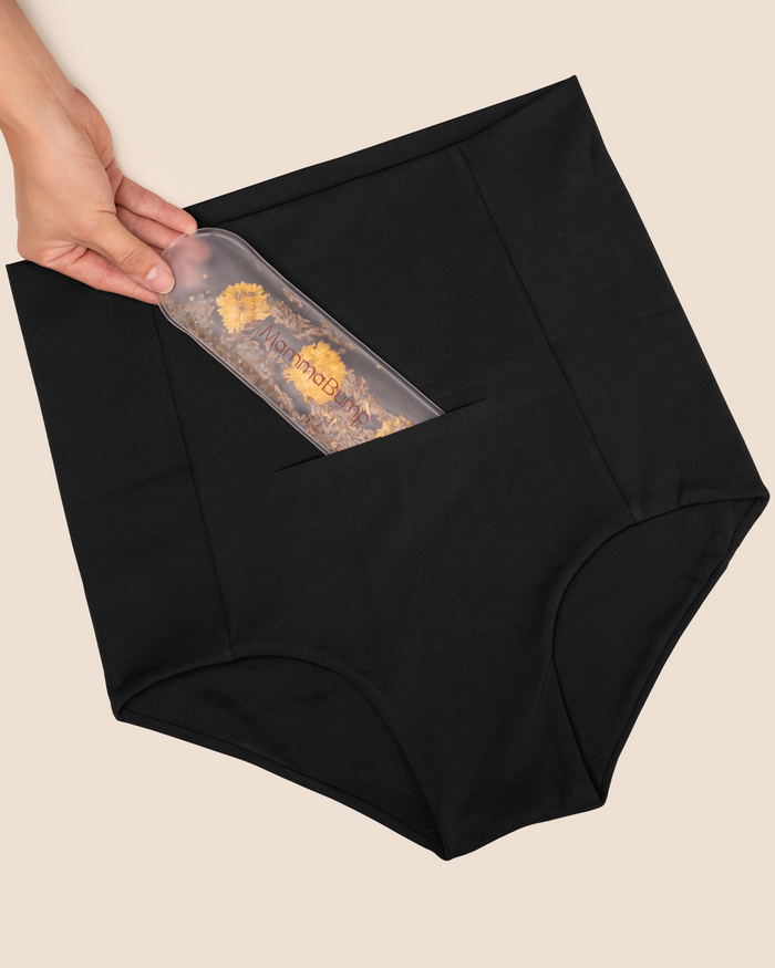 Hand placing the MammaBump Perineal Hot & Cold Therapy Pack into the pocket of the Postpartum Soothing Brief for gentle perineal relief during postpartum recovery