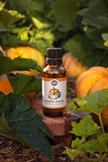 Rustic Strength - Phthalate-Free Fragrance Oil | 1oz Amber Glass Vial | Pumpkin Harvest, set on a wooden stand in a pumpkin patch