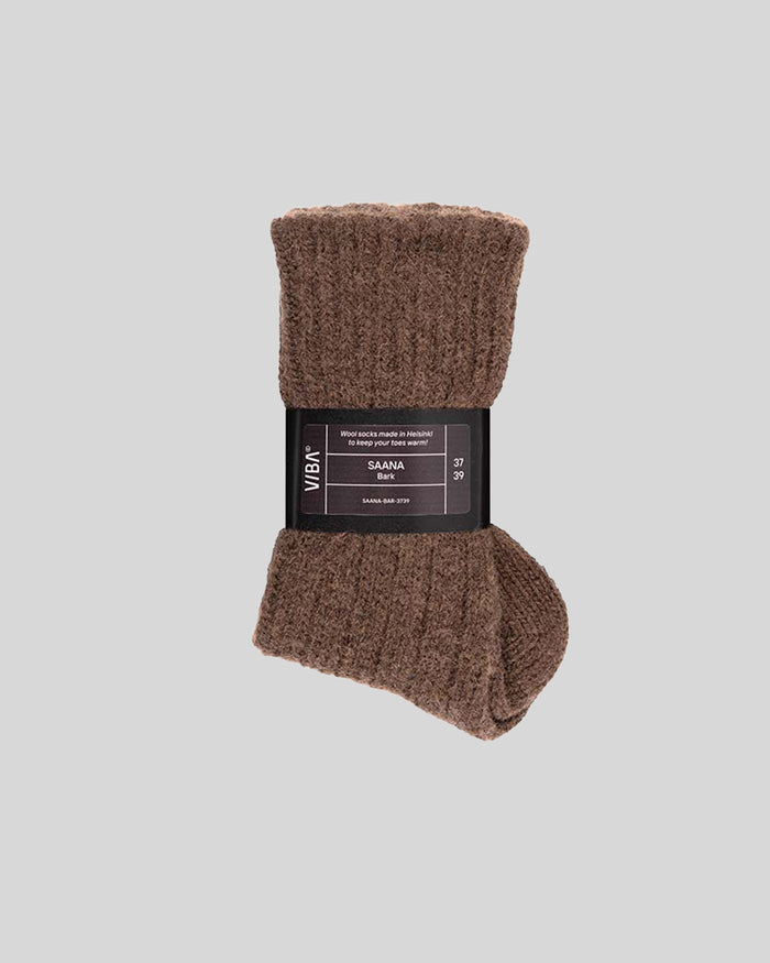 Brown wool socks with ribbed texture and black label band marked "SAANA Bark."