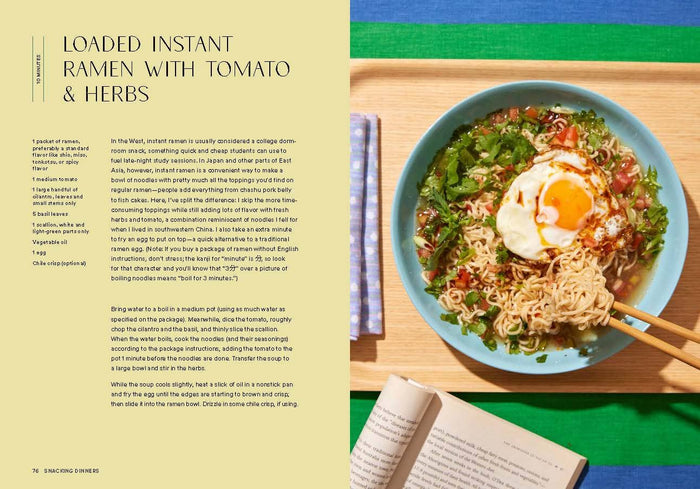 Loaded instant ramen with tomato and herbs on a wooden tray, with an open book beside it.